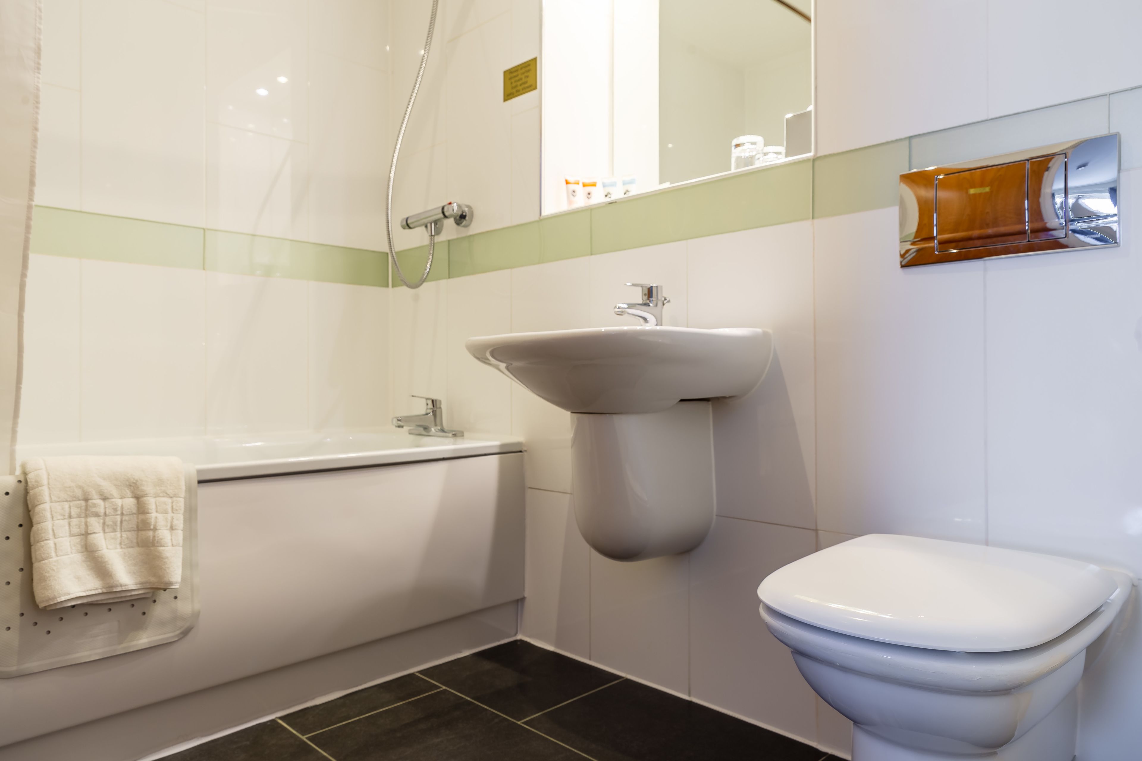 Ein modernes Badezimmer mit einer weißen Badewanne, einem Standwaschbecken und einer Toilette.