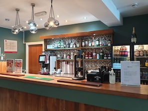 A bar area with a coffee machine, stacked glasses, and a variety of liquor bottles. - Legacy Preston International Hotel (Preston)