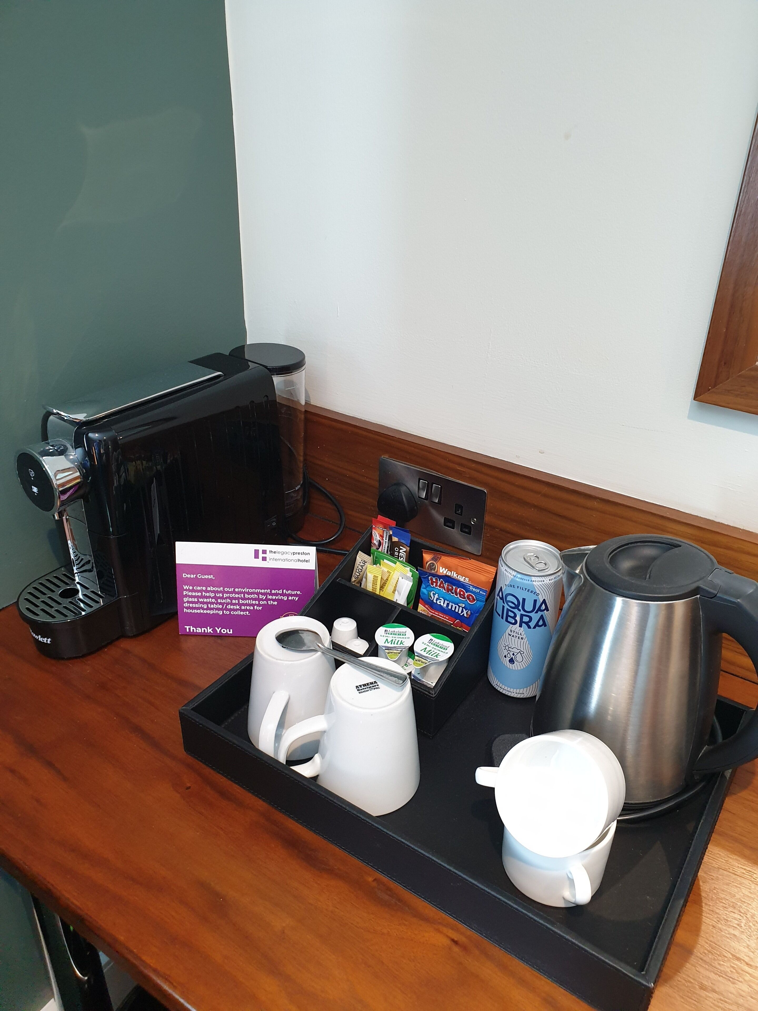 Bandeja de desayuno en una habitación de hotel con cafetera, tetera, taza y una lata de agua.