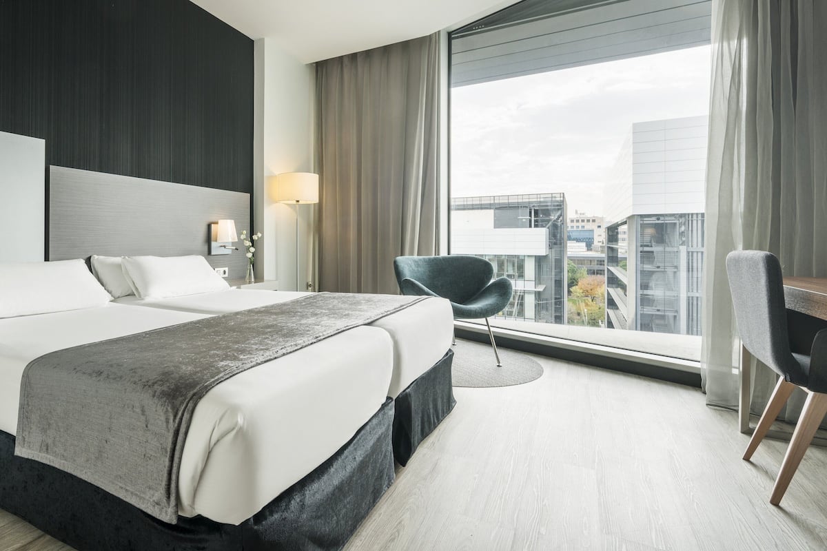 Una camera d'albergo moderna con un letto grande, una scrivania e vista sulla città.