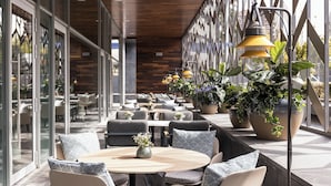 Un espace extérieur moderne, aménagé avec des tables et des chaises rondes, des plantes en pot et un plafond en bois.