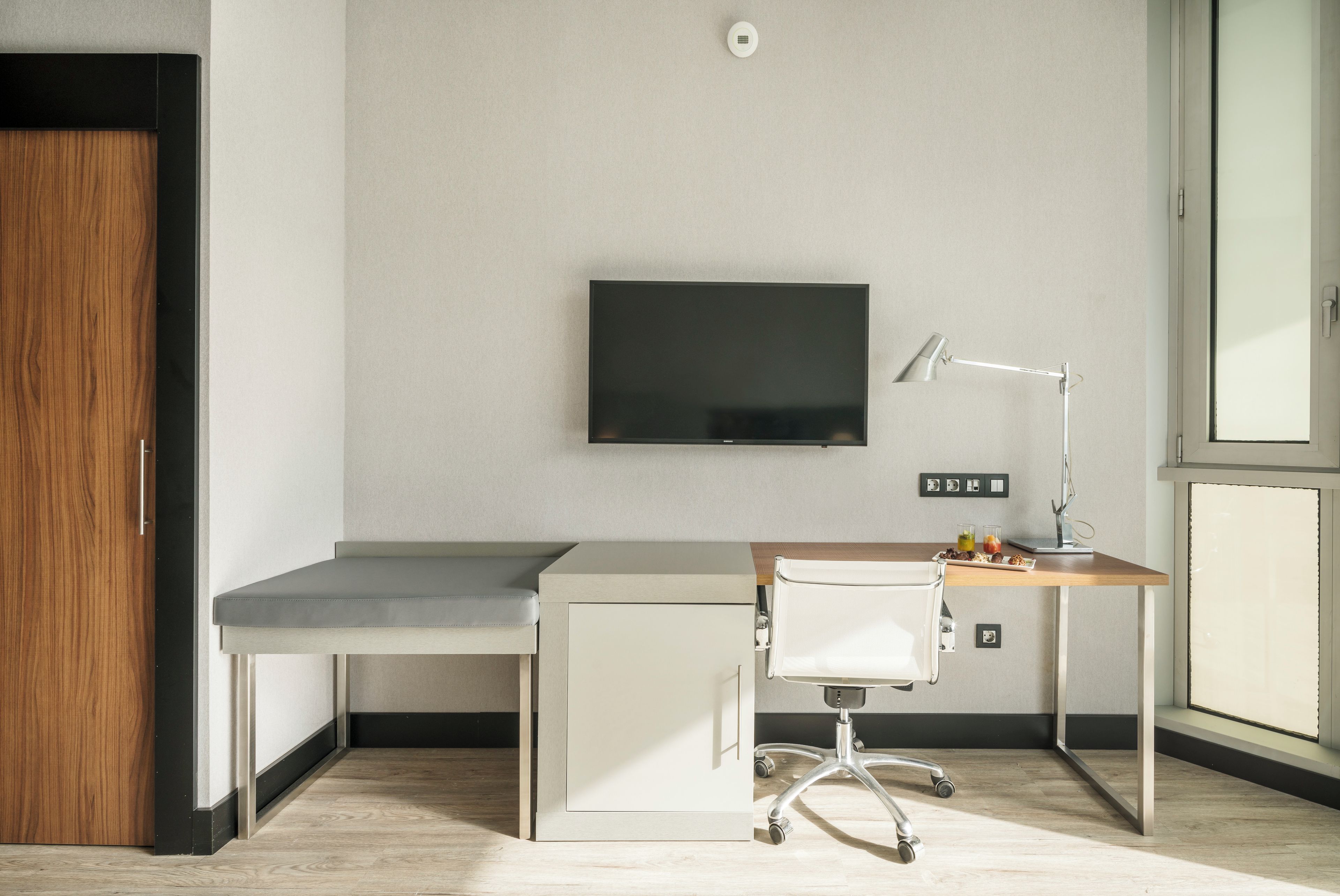 Despatx modern amb escriptori, cadira, televisió i finestra.