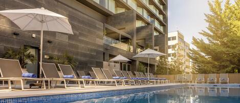 Una piscina al aire libre de temporada, sombrillas