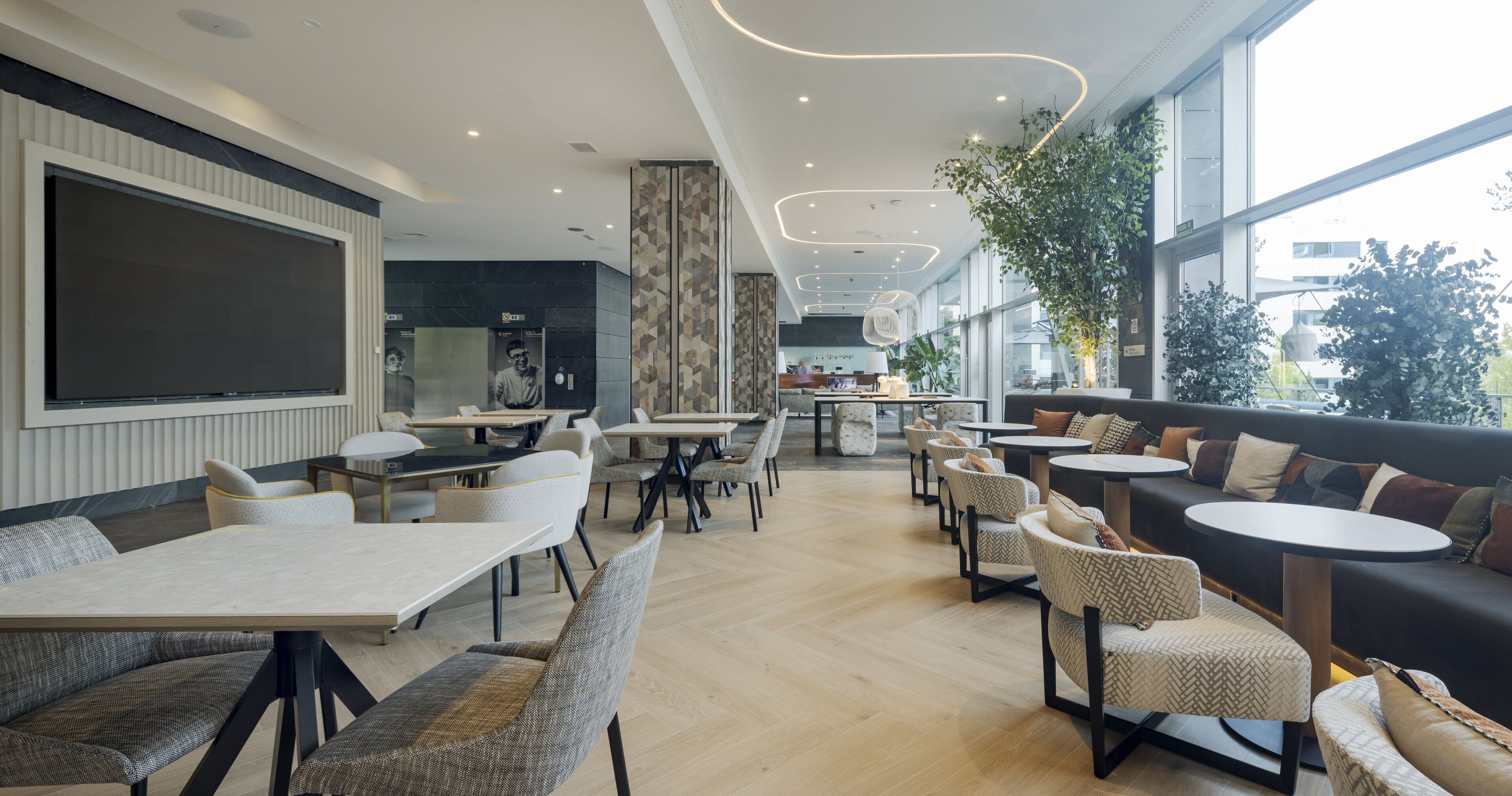 Um restaurante moderno com diversas opções de assentos, incluindo mesas e cabines, e uma grande janela que oferece vista da cidade.