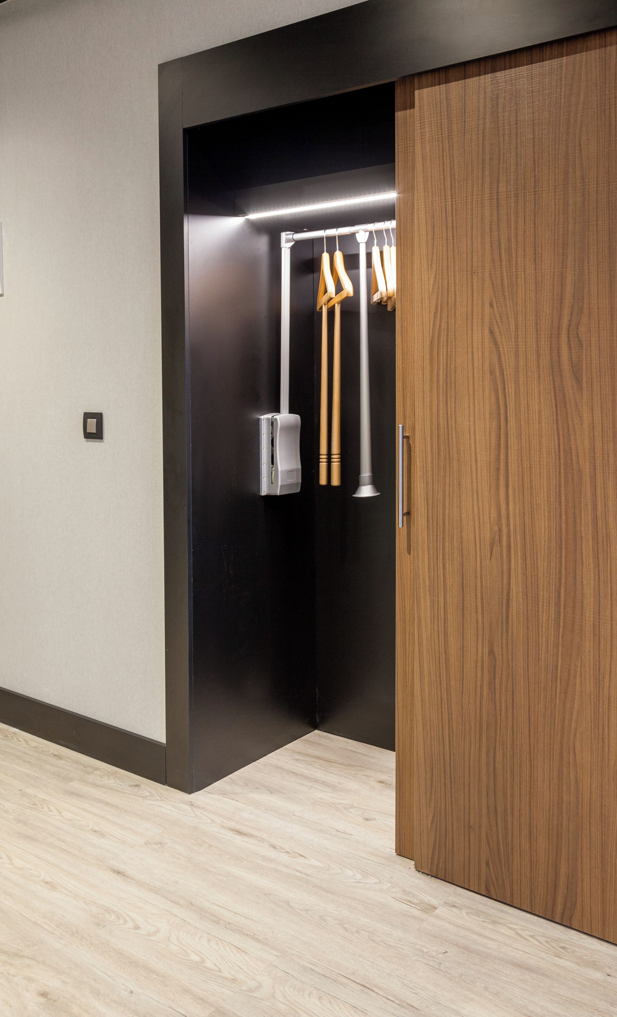 Ein modernes Zimmer mit Holzboden, einer schwarzen Wand und einem Holzschrank.