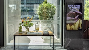 Un intérieur moderne avec une cloison en verre, une petite table sur laquelle est posé un vase de fleurs et une affiche accrochée au mur.