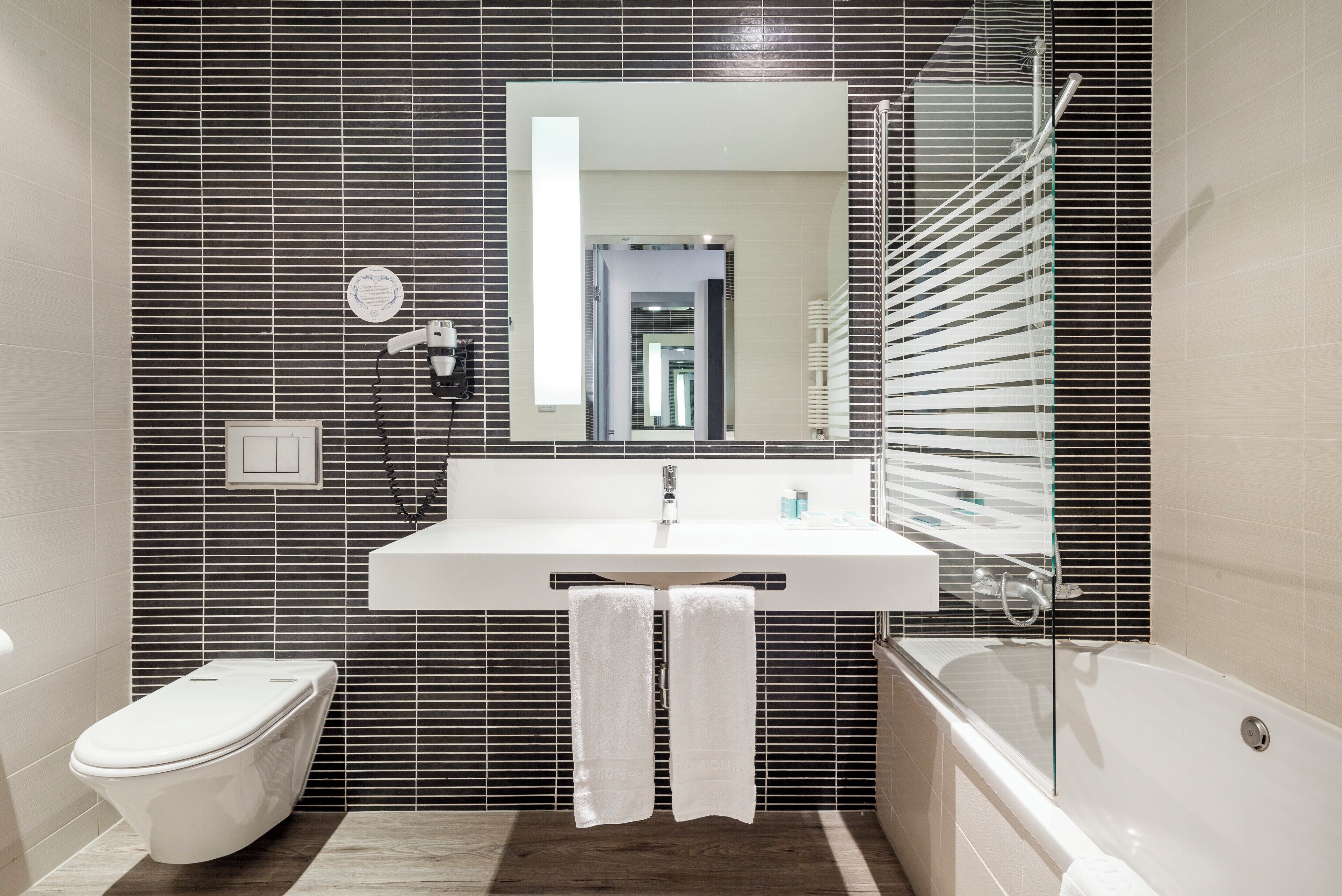 A modern bathroom with a white sink, a toilet, and a bathtub.