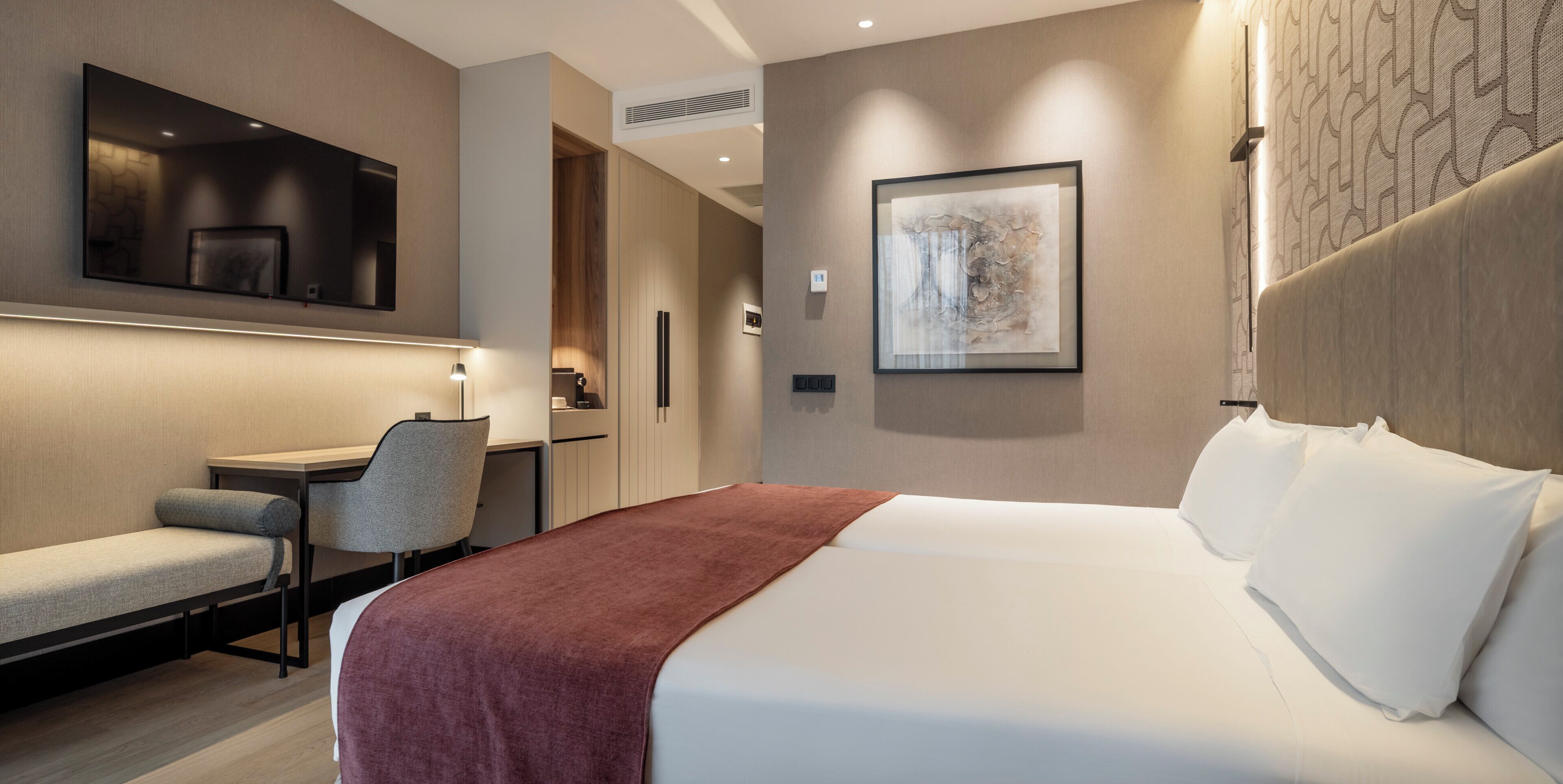 Una habitación de hotel moderna con una cama, un escritorio y una silla.