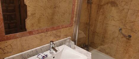 A bathroom with a marble sink, a bathtub, and a glass shower enclosure.