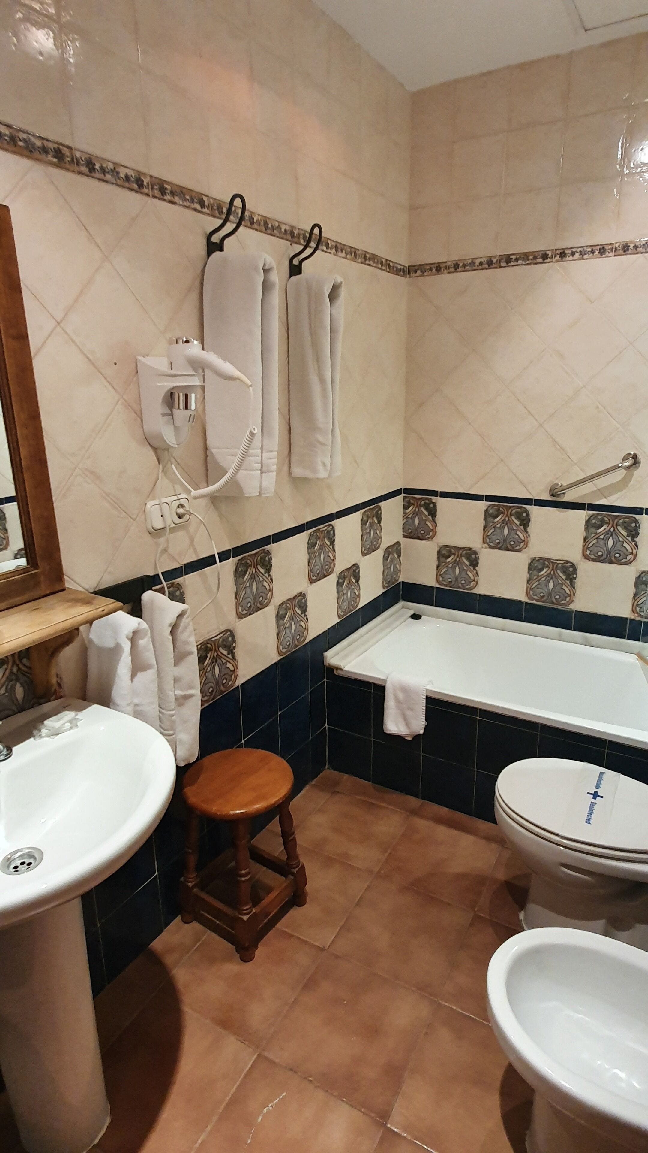 A bathroom with a sink, toilet, and bathtub. There are towels hanging on hooks and a mirror above the sink.