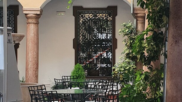 An outdoor dining area with a table and chairs, surrounded by potted plants and a decorative metal gate. - Hotel Coso Viejo (Antequera)