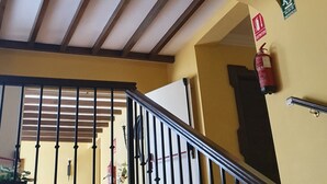 A staircase with a metal railing, a ceiling light fixture, and a fire extinguisher on the wall. - Hotel Coso Viejo (Antequera)