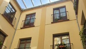 A building with a glass ceiling, multiple balconies with plants, and a courtyard with columns. - Hotel Coso Viejo (Antequera)