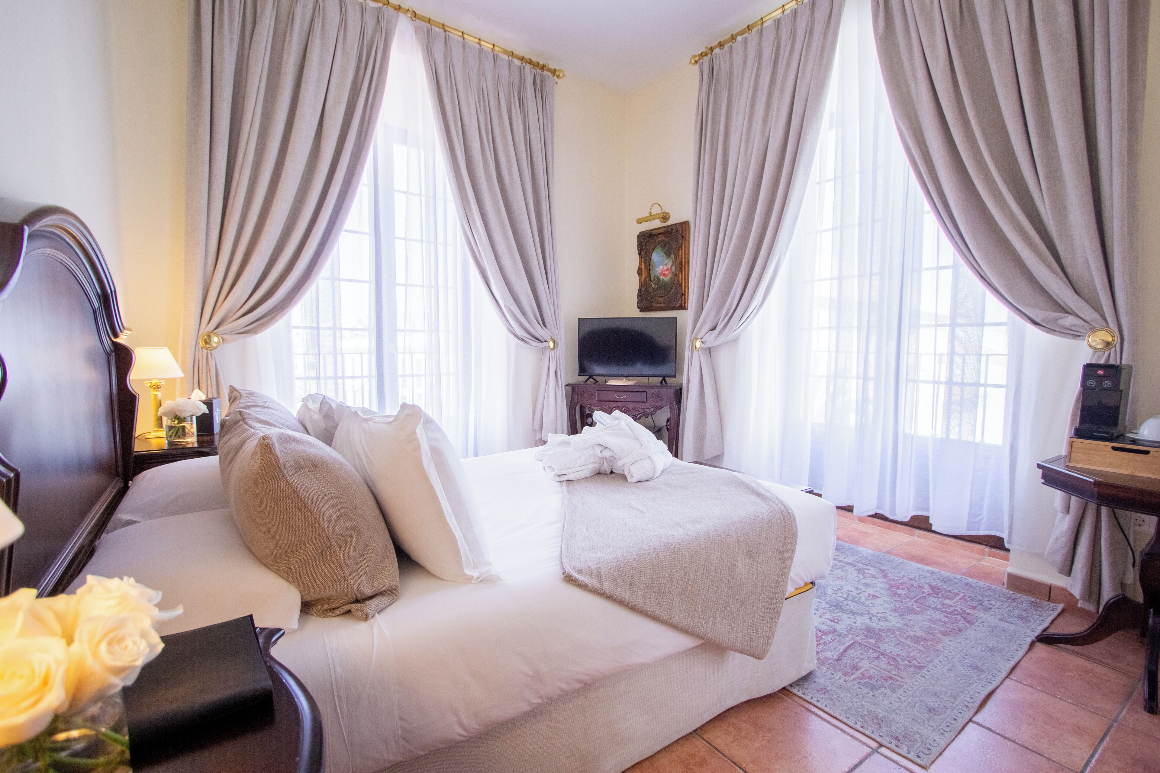 Habitación de hotel con cama, televisión, escritorio y cortinas.