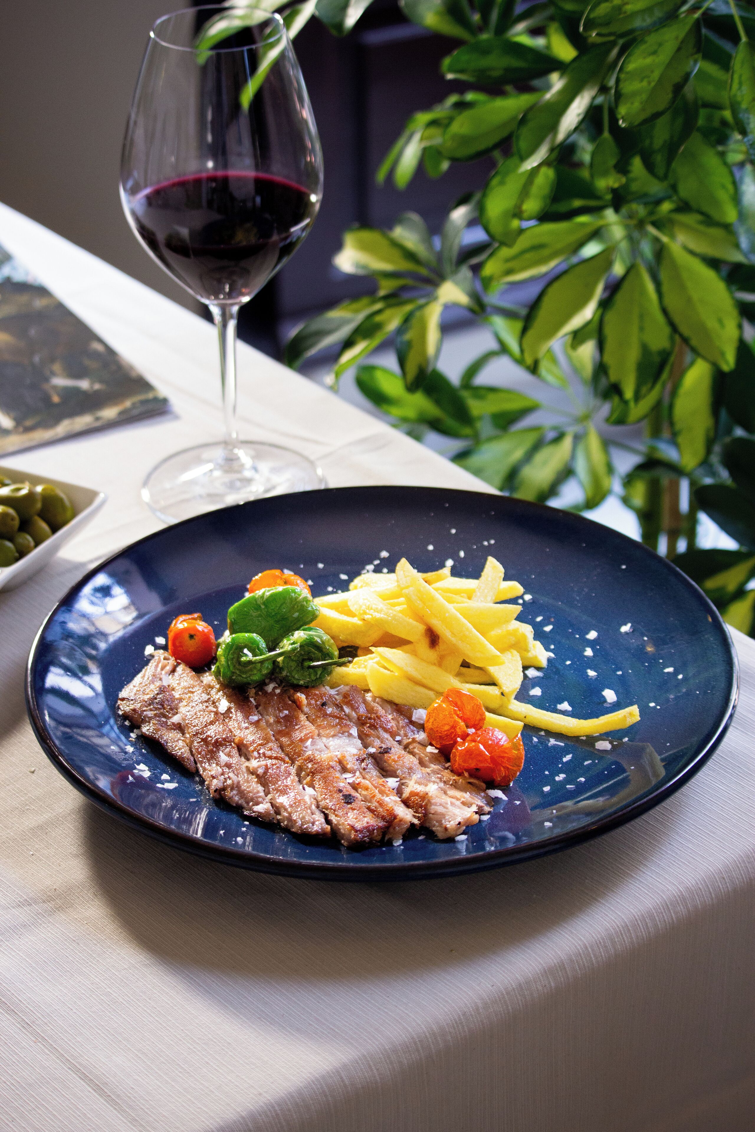 Une assiette contenant un steak, des frites et des légumes, ainsi qu'un verre de vin rouge, posée sur une table.