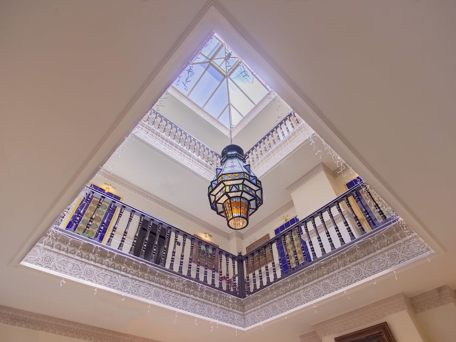 Una habitación con techos altos, tragaluces, un farol decorativo y barandilla de balcón con diseño.