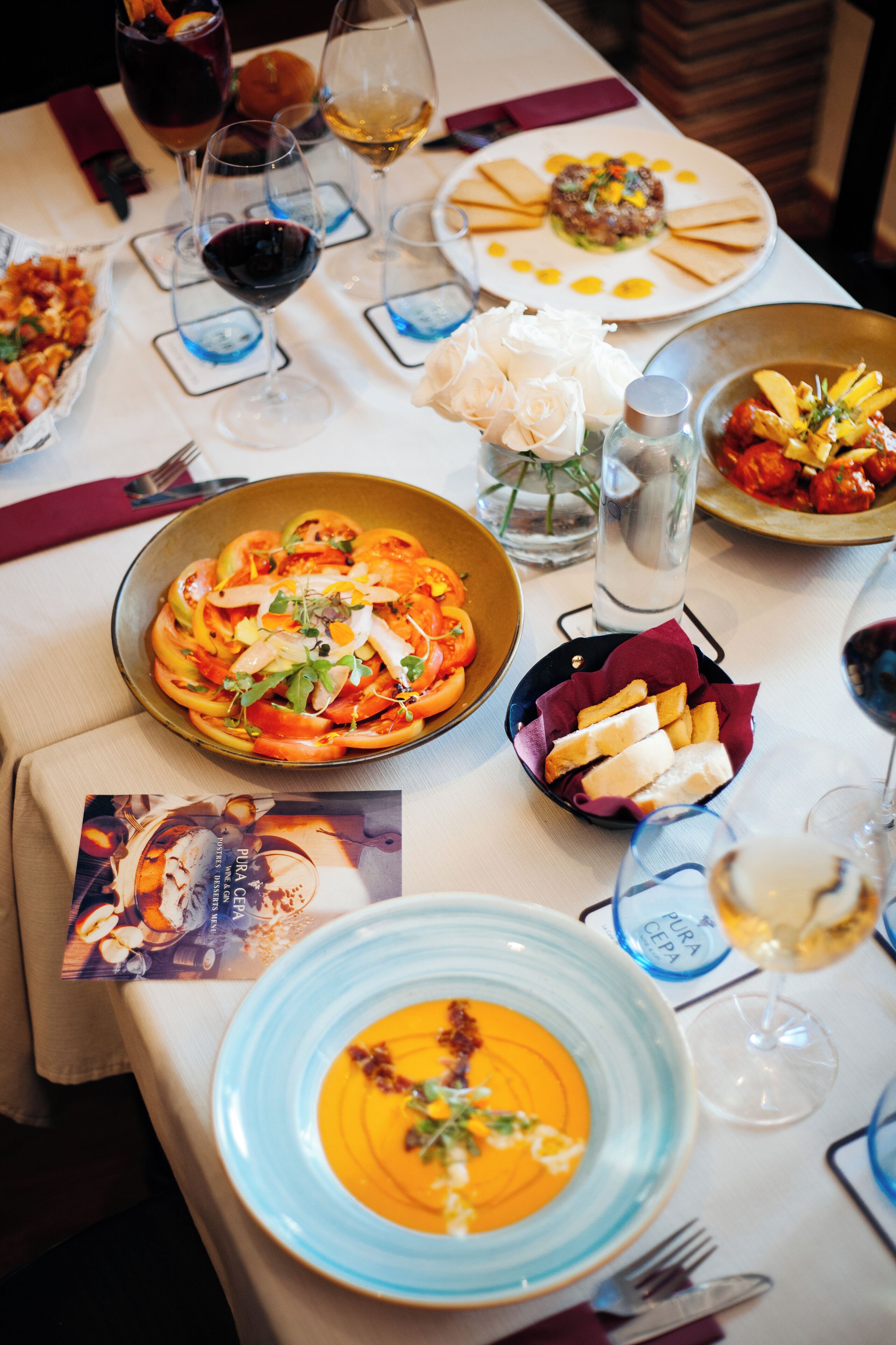 A dining table with various dishes, wine glasses, and a menu.