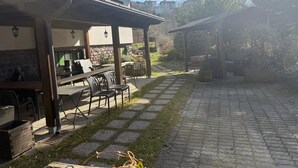 An outdoor patio area with a covered seating area, stone pathway, and a view of surrounding buildings. - Hotel Ristorante Sassi Rossi  (Crandola Valsassina)