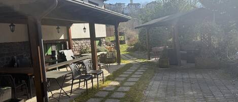 An outdoor patio area with a covered seating area, stone pathway, and a view of surrounding buildings.