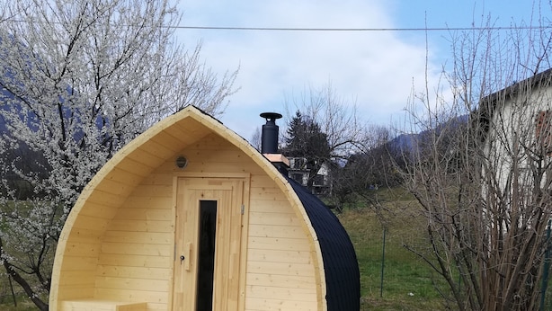 A wooden cabin with a door, a bench, and a fireplace. - Hotel Ristorante Sassi Rossi  (Crandola Valsassina)