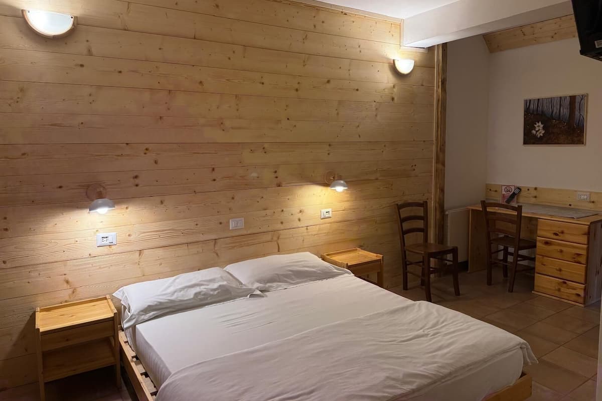 Une pièce aux murs lambrés, comprenant un lit, des tables de chevet, un bureau et une chaise.
