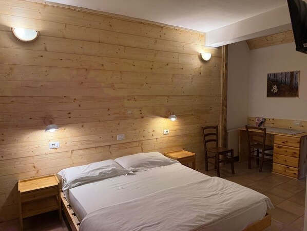 A wooden-paneled room with a bed, bedside tables, a desk, and a chair. - Hotel Ristorante Sassi Rossi  (Crandola Valsassina)