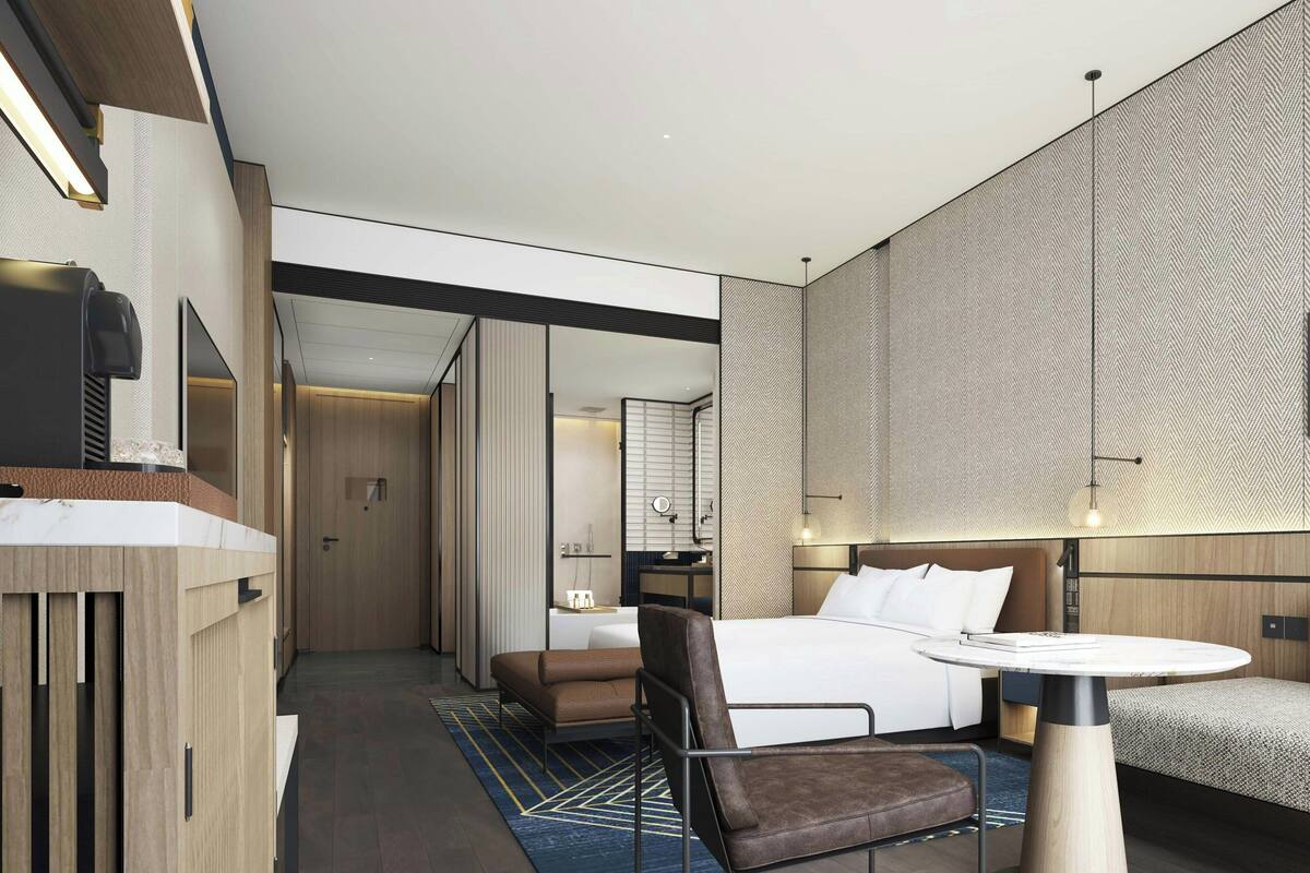 Une chambre d’hôtel moderne équipée d’un grand lit, d’un bureau, d’une chaise et d’une petite table.