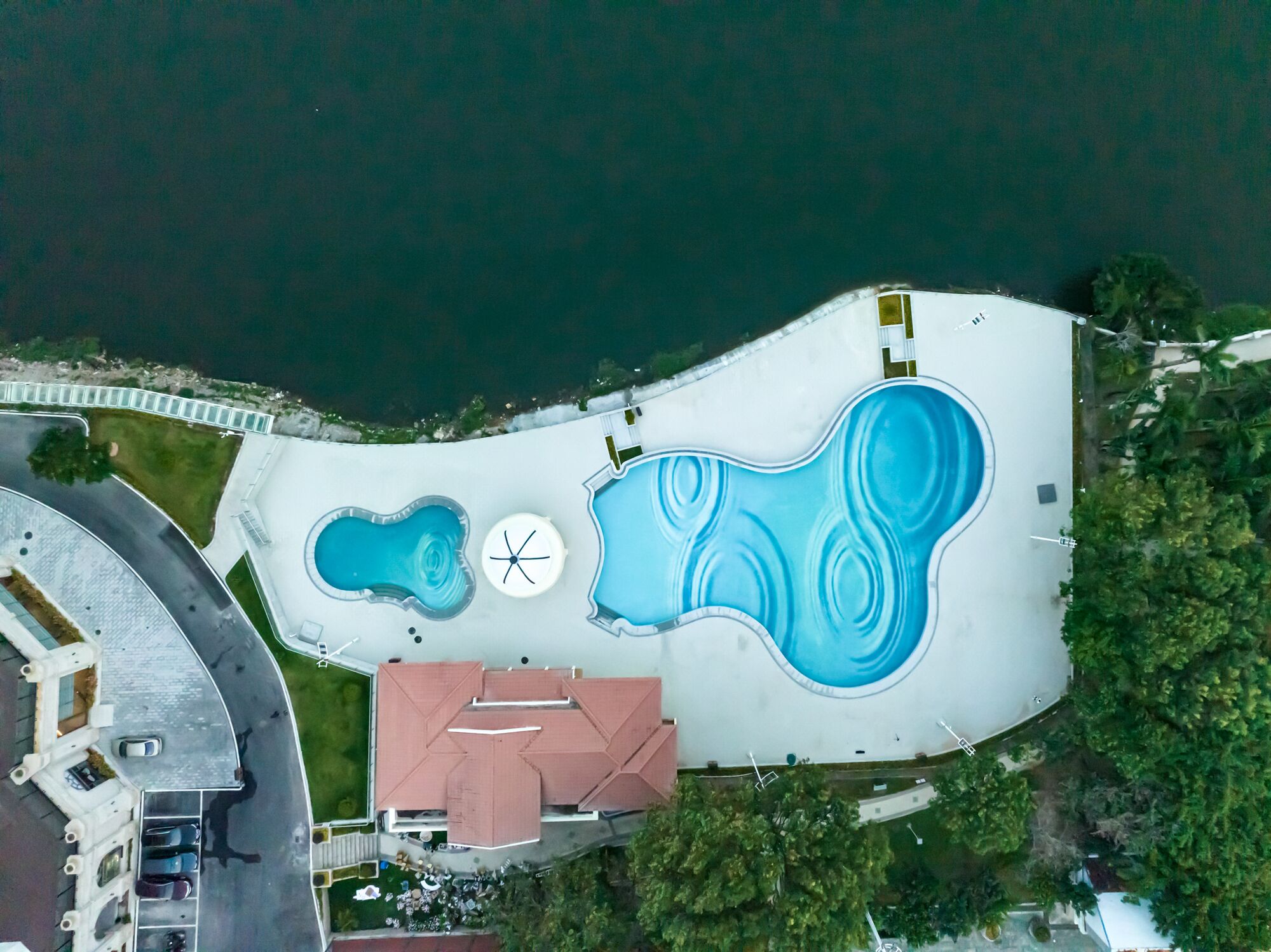 Vista aérea de una propiedad con piscina, zona cubierta y aparcamiento.