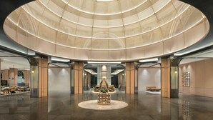 A spacious lobby with a central decorative feature, a large circular ceiling, and a polished floor.