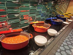 A buffet setup with various dishes in different colored serving containers.