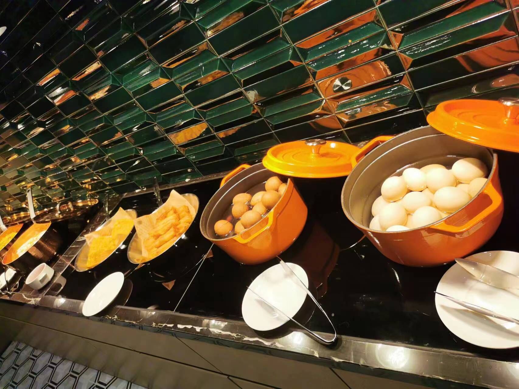 A buffet setup with various food items in orange and green containers.