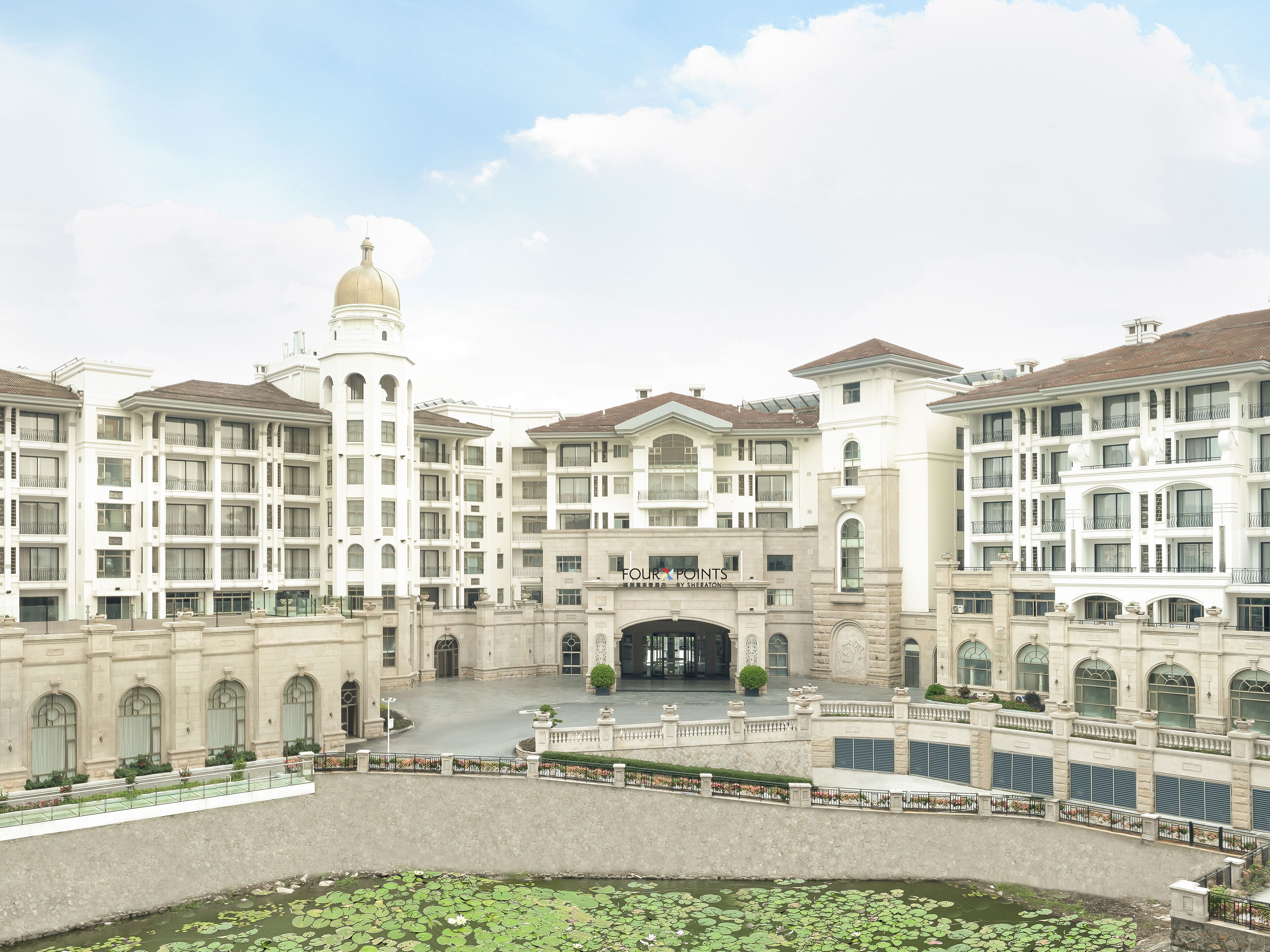 Un grand hôtel à plusieurs étages, doté d’une cour intérieure et d’un bassin orné de nénuphars.