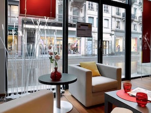 En modern inredning med en soffa, ett litet bord med en vas och utsikt över gatan utanför.