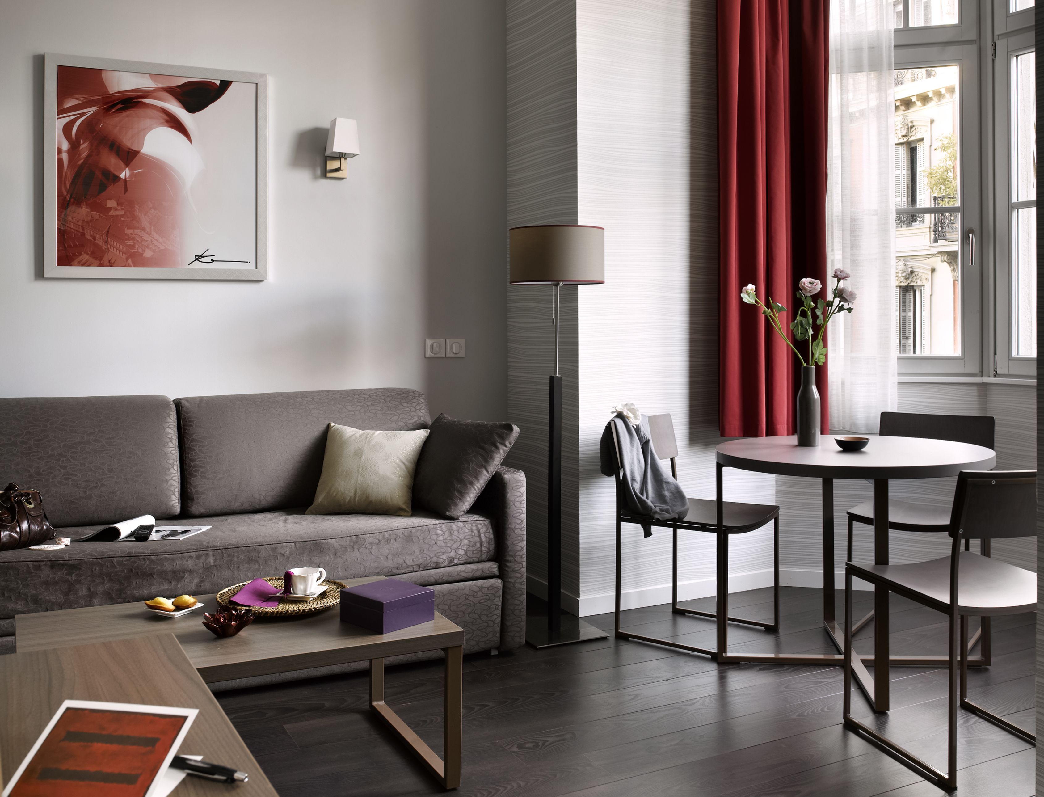 A modern living room with a grey sofa, a round dining table, and a floor lamp.