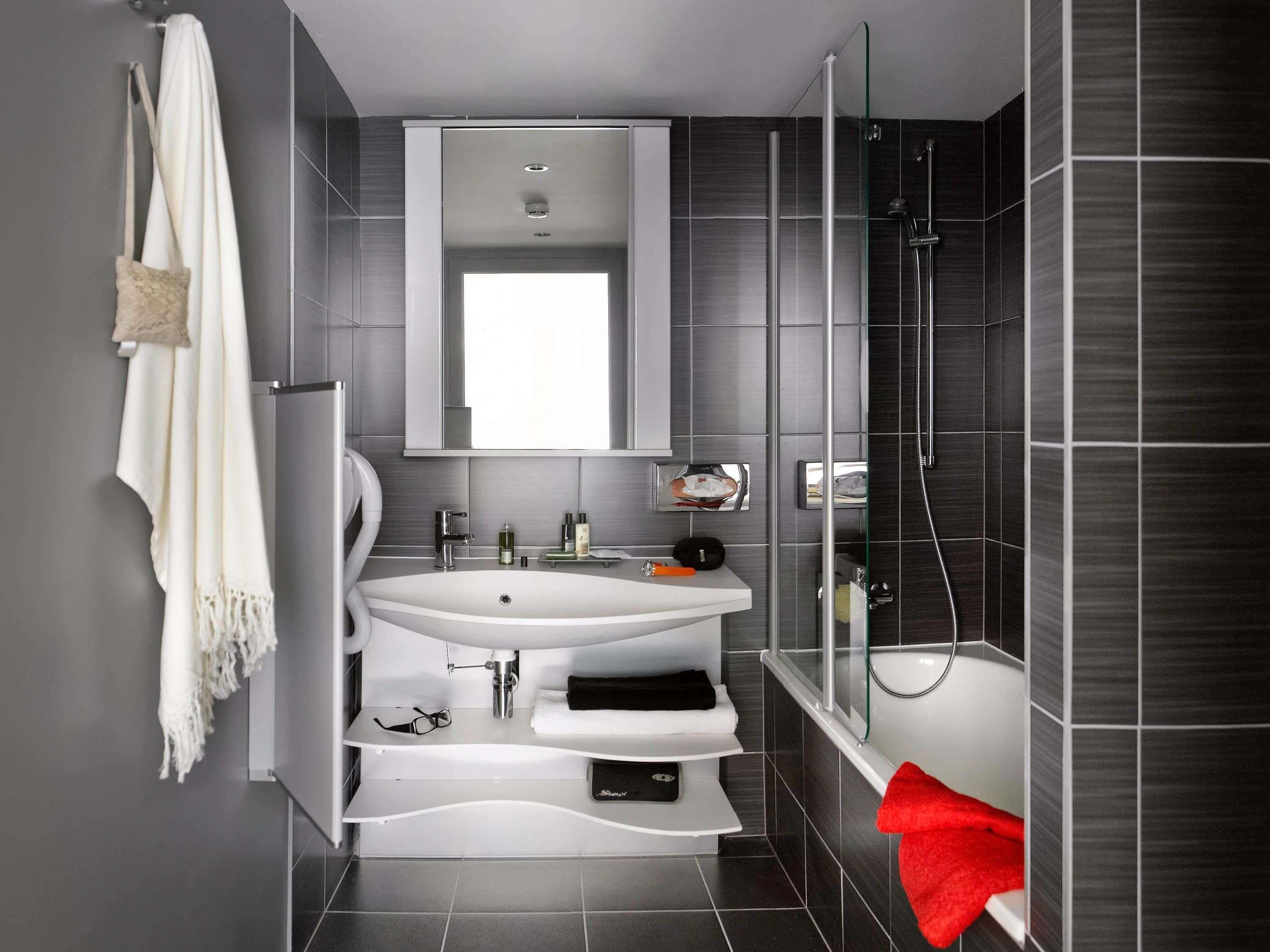 A modern bathroom with a large white sink, a glass-enclosed shower, and a mirror above the sink.
