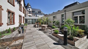 A courtyard with wooden decking, outdoor seating, and planters.