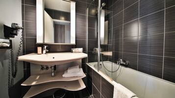 A modern bathroom with a large mirror, a sink, a bathtub, and a shower.