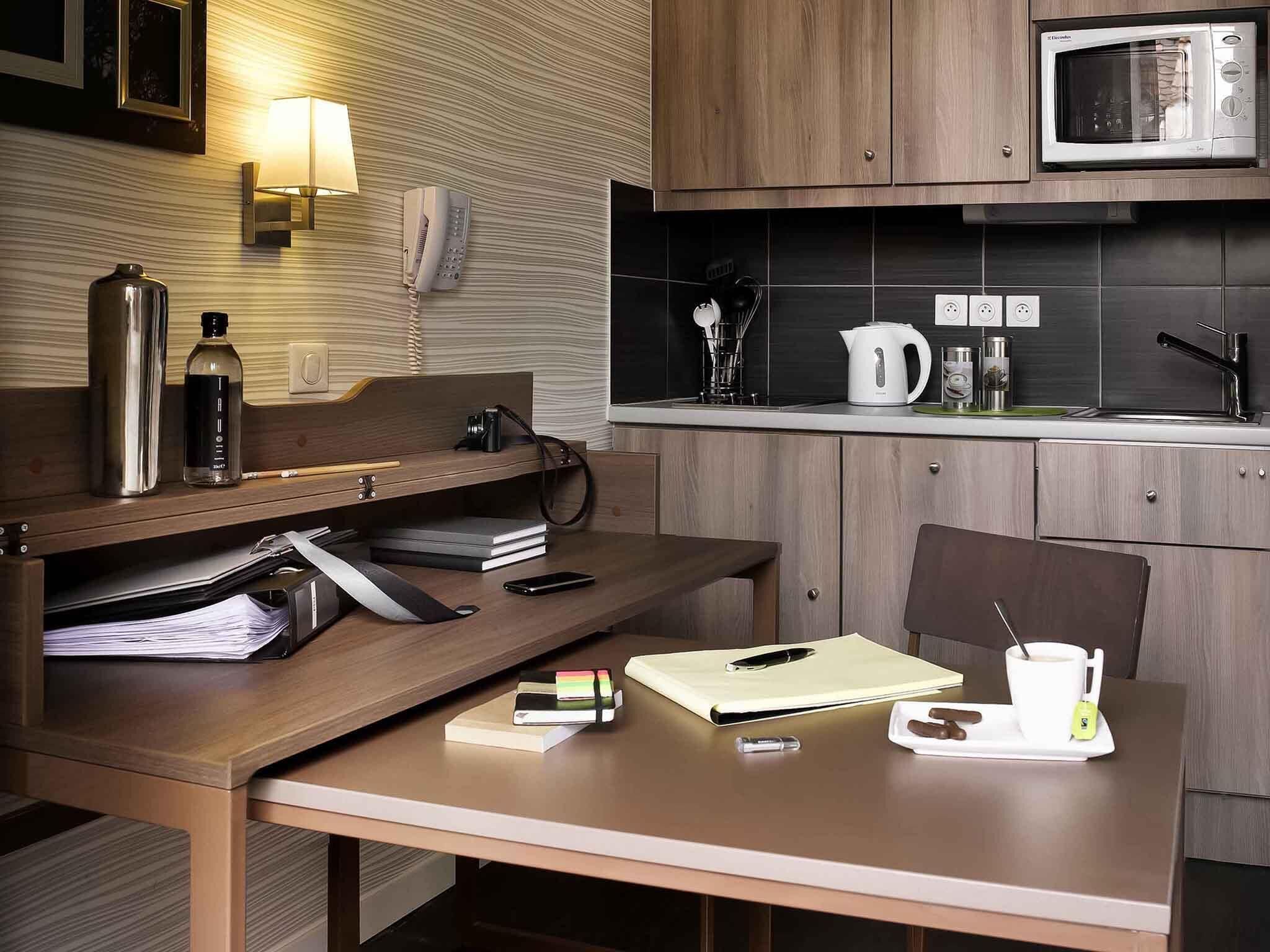 Una cocina compacta con microondas, hervidor y cafetera sobre la encimera.