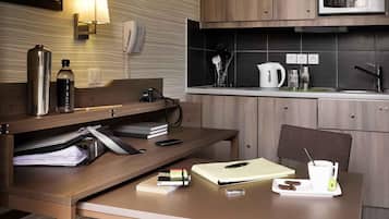 Una cocina compacta con microondas, hervidor y cafetera sobre la encimera.