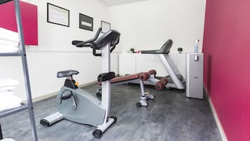 A gym with exercise equipment, a treadmill, and a small refrigerator.