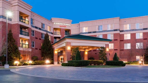 Un hotel Courtyard Marriott con fachada de ladrillo, varios balcones y una zona de acceso cubierta.