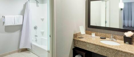 Une salle de bain moderne avec une douche en verre, un lavabo doté d’un plan de travail en granit et un grand miroir.