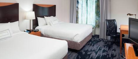 A hotel room with two beds, a desk, a chair, a television, and a window with curtains.