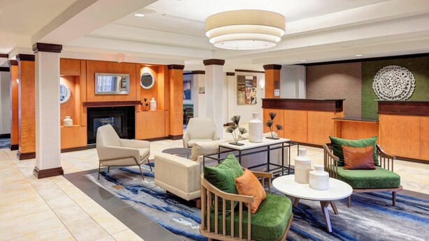 A spacious lobby with a fireplace, comfortable seating, and a decorative rug. - Fairfield Inn & Suites by Marriott Wilmington/Wrightsville Beach (Wilmington)