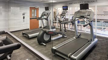 A gym with treadmills, exercise bikes, and a mirrored wall.
