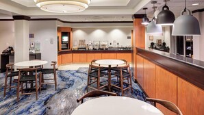 A hotel lobby with round tables and chairs, a reception desk, and a counter with various amenities. - Fairfield Inn & Suites by Marriott Wilmington/Wrightsville Beach (Wilmington)