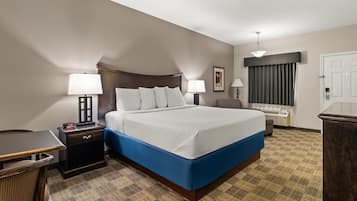 Una habitación de hotel con una cama grande, dos mesitas de noche con lámparas, un escritorio y una silla.