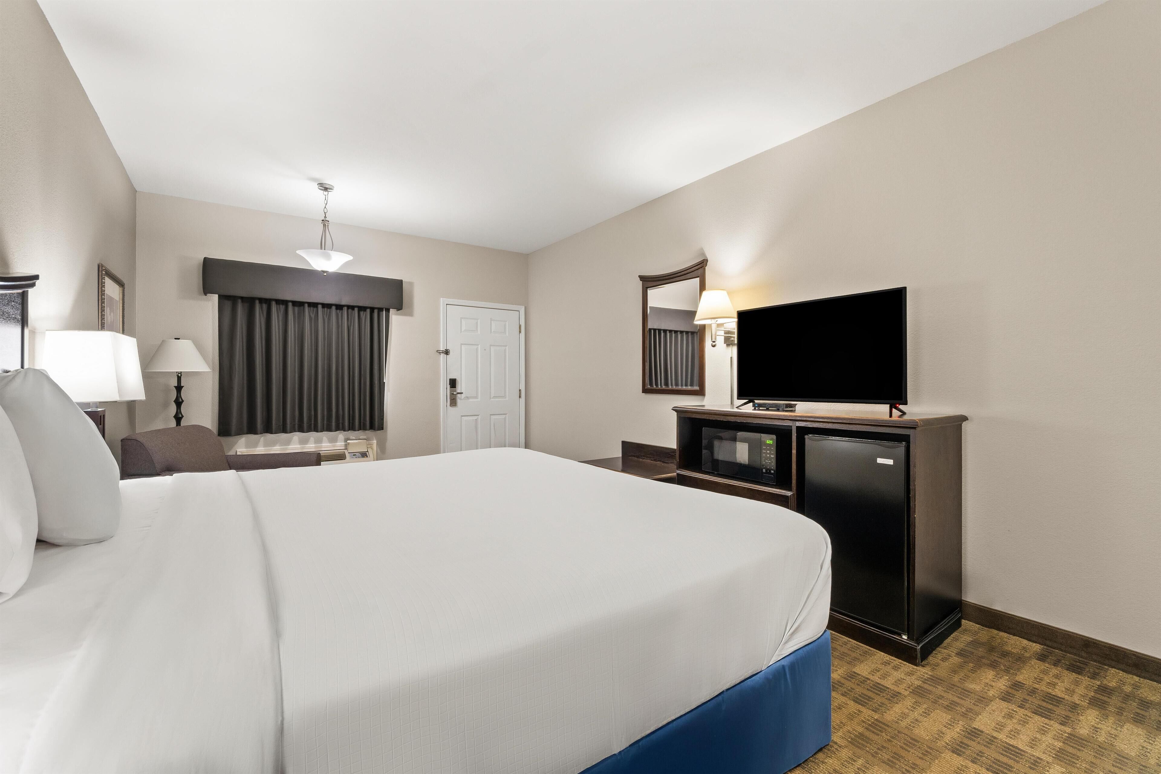 Habitación de hotel con una cama grande, un escritorio con computadora, televisión y armario.