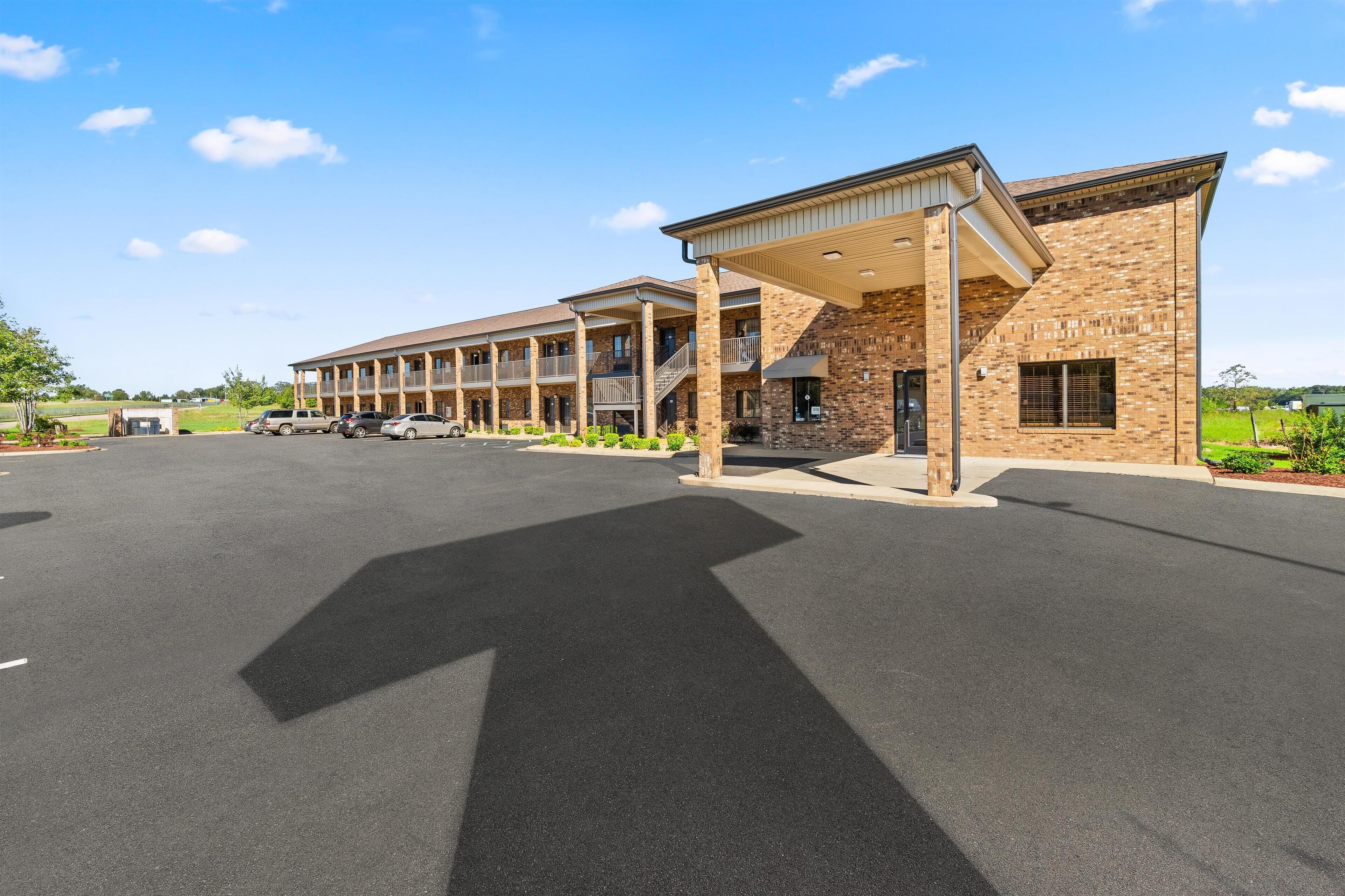 A motel with multiple units, covered parking, and a landscaped area.