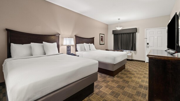 A hotel room with two beds, a desk, a television, and a window with curtains. - Americas Best Value Inn Byhalia (Byhalia)